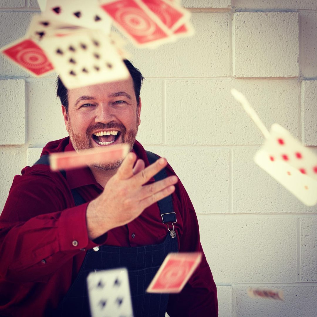 A playful and energetic moment as Matt Donnelly tosses playing cards into the air, embodying the joy and wonder of magic.