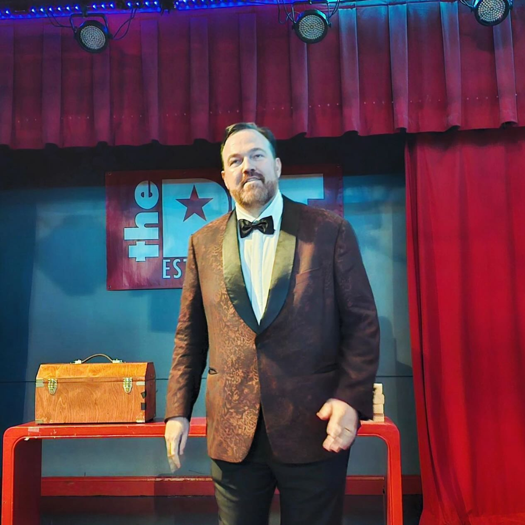 Under the glow of stage lights, Matt Donnelly prepares to perform, standing confidently before an eager audience.